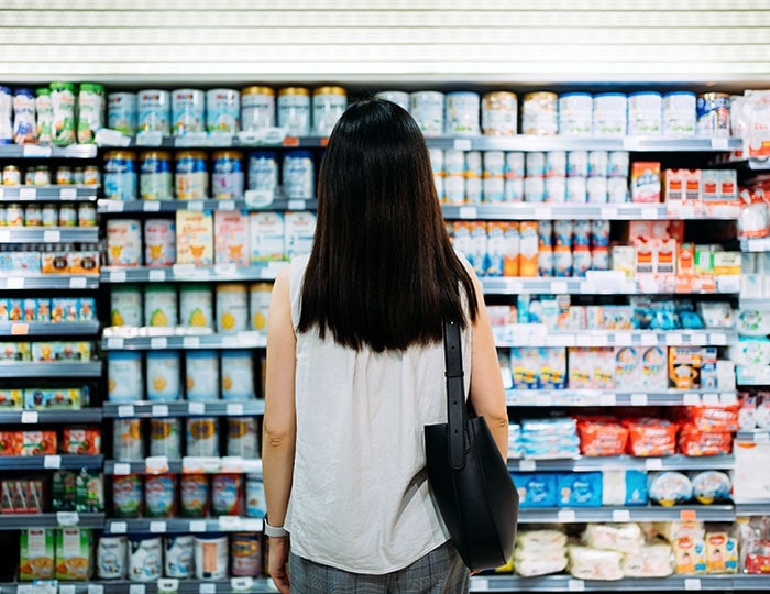Woman in supermarket with lots of items on shelves