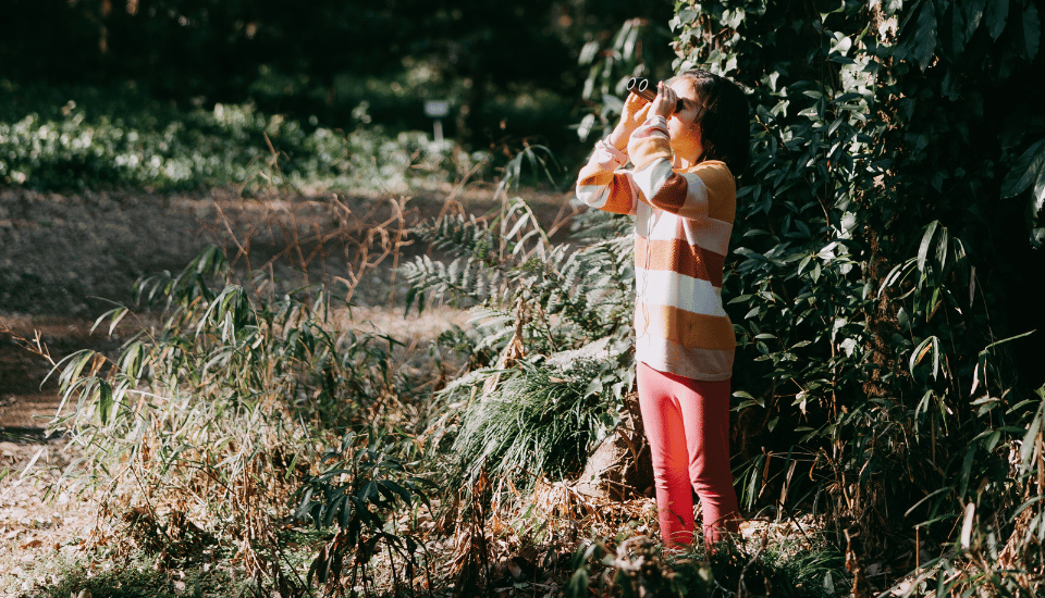 Girl with binoculars in forest