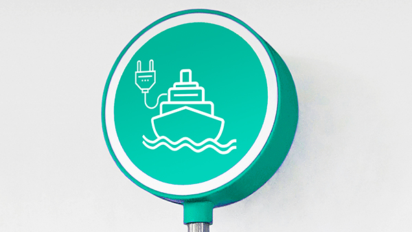 A circular teal sign with a white border features an icon of a ship on waves, connected to a power plug, symbolizing electric or eco-friendly shipping.