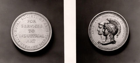 Two sides of a medal. The first side reads: "Royal Society of Arts For Services To Industrial Art Bicentenary Medal." The second side features two busts in profile, adorned with helmets and laurels, with the text: "Royal Farmers and Commerce Progresses.