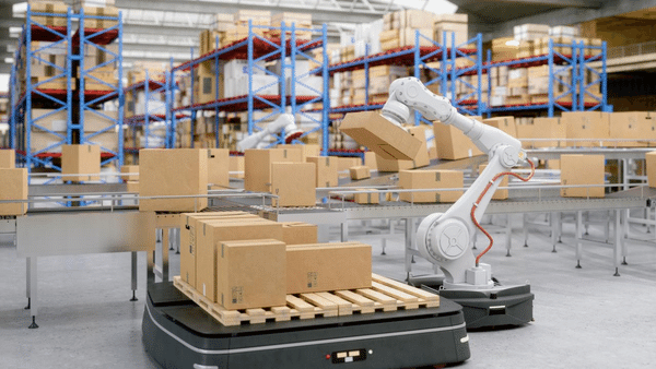 Robotic arms efficiently handling boxes on a conveyor belt in a modern warehouse. Shelves filled with more boxes are visible in the background, showcasing an automated logistics system.