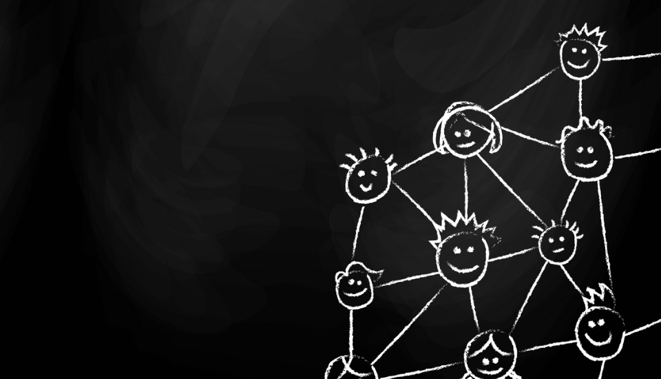 Chalk drawing on a blackboard of connected smiling stick figure faces forming a network with lines.