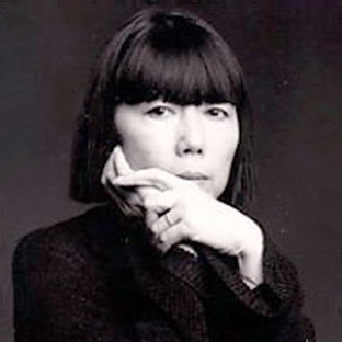 A person with a bob haircut and bangs is looking thoughtfully at the camera, resting their chin on their crossed hands. The image is black and white, giving a classic, timeless feel.