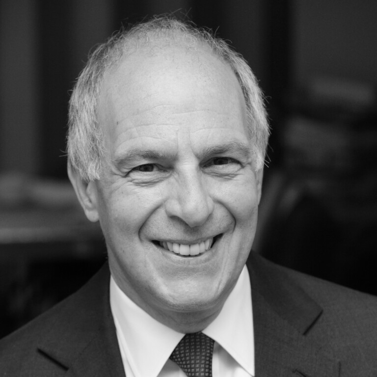 Elderly man smiling while wearing a suit and tie, captured in a black-and-white photograph. Join us to celebrate the opening of the UK Pavilion at Expo 2025 Osaka, where timeless elegance meets groundbreaking innovation from the UK and Japan.