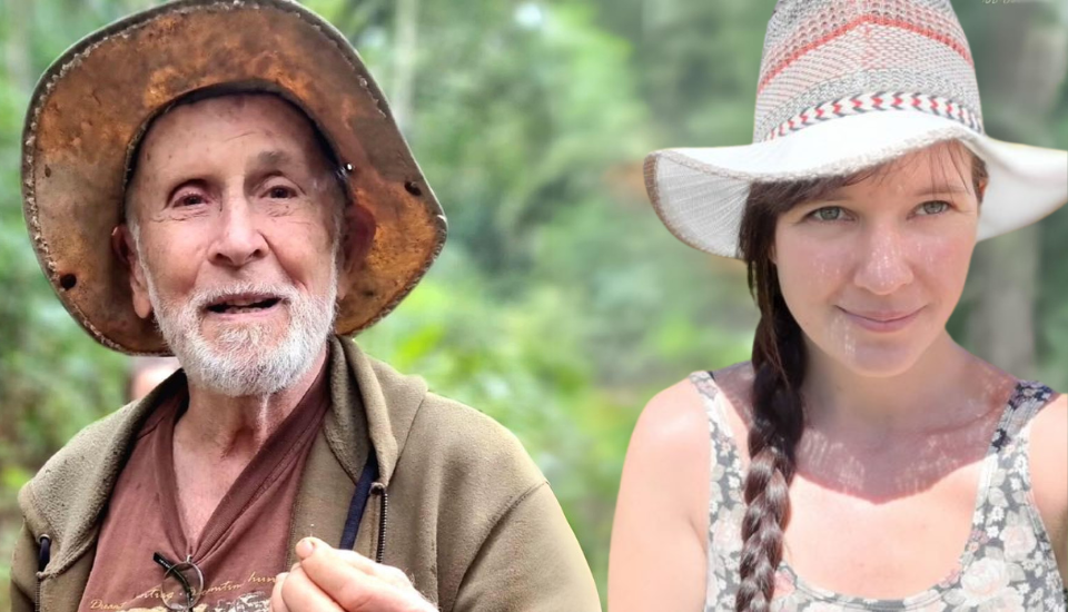 An elderly man with a beard and a brown hat stands next to a smiling woman with a braided hairstyle and a straw hat. They are outdoors with greenery in the background.