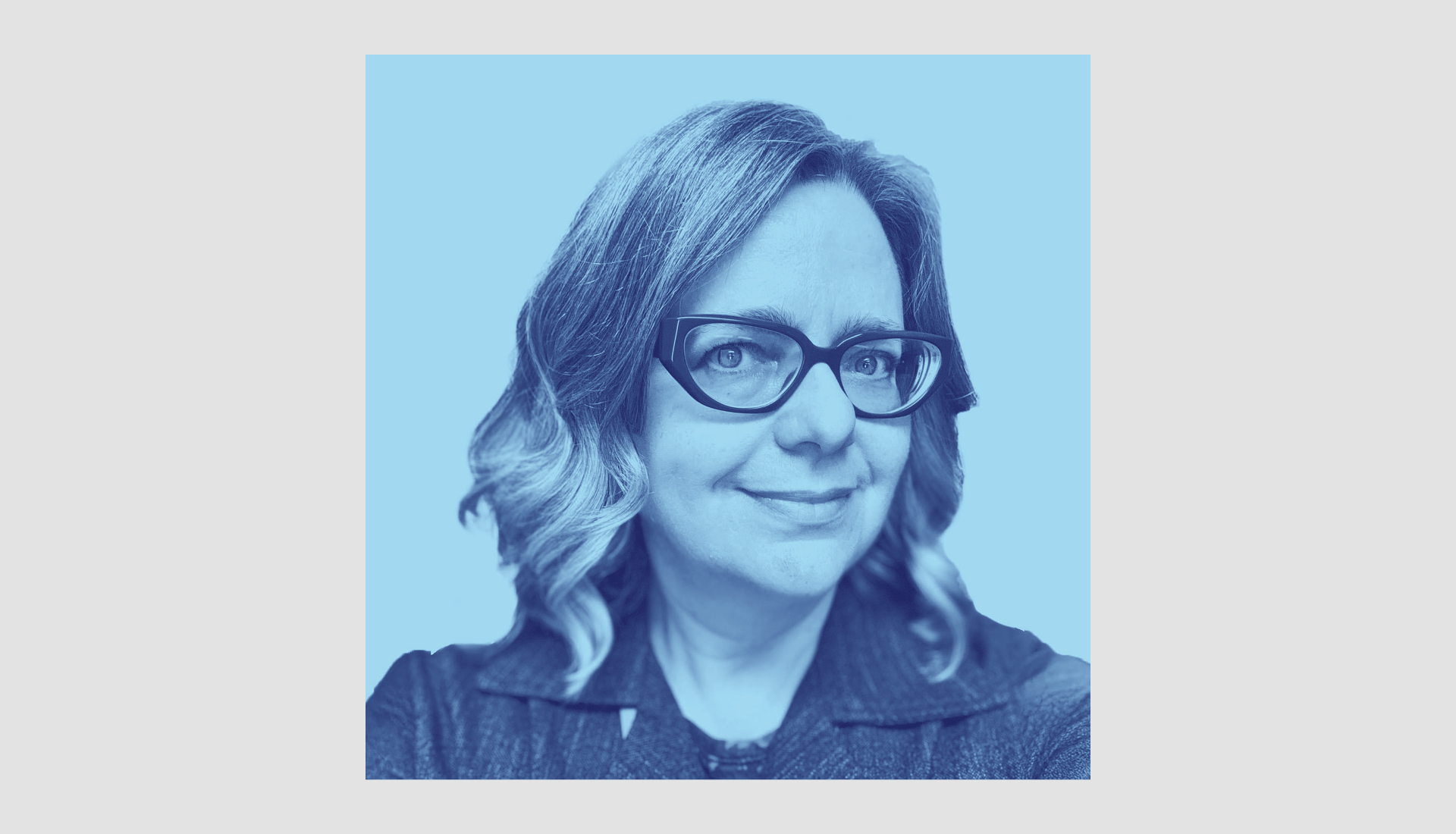 An image of Johanna Mizgala with shoulder-length wavy hair and glasses smiles slightly. The image has a blue monochrome filter and a light blue background.
