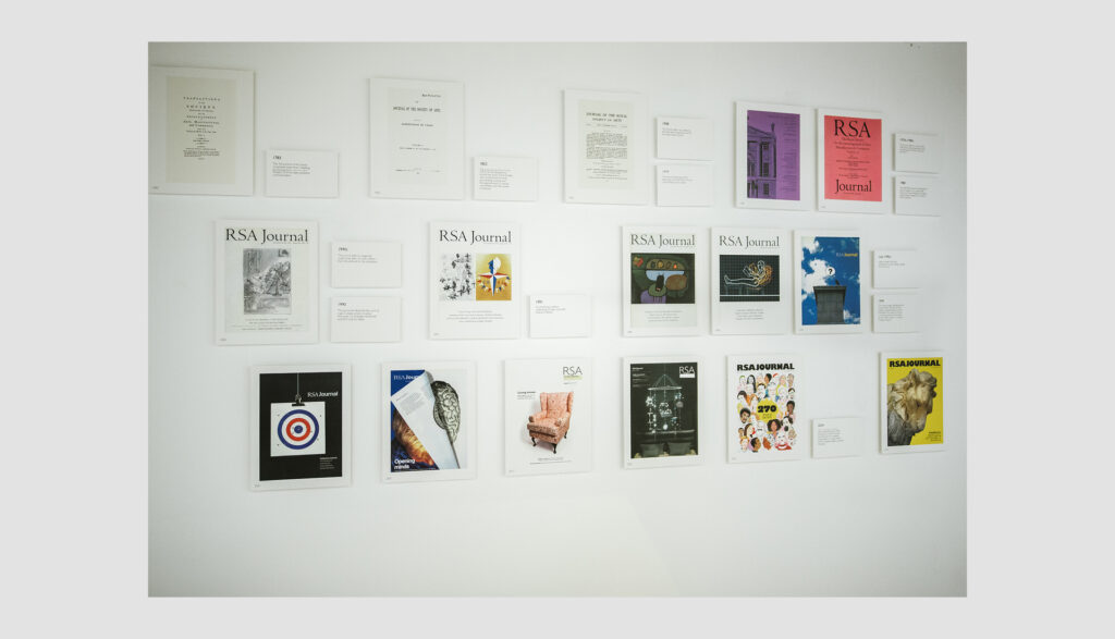 A display of various RSA Journal covers and pages arranged in a grid on a white wall, featuring different designs, colors, and images, including artwork, portraits, and text.