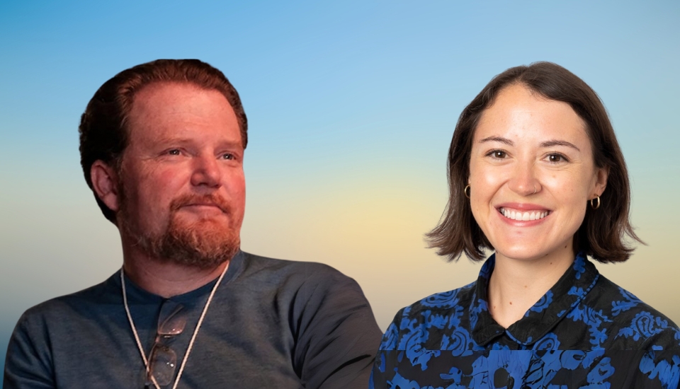 A man with a beard and glasses on his shirt sits next to a smiling woman with short dark hair, wearing a blue and black patterned shirt, against a gradient sky background.