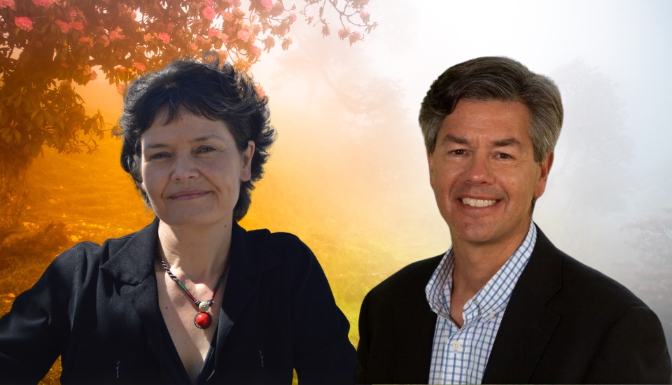 A woman and a man, both in business attire, smile at the camera. Behind them is a misty backdrop with warm sunlight and flowering tree branches.