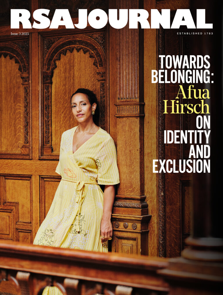 Afua Hirsch in a yellow dress stands by a wooden wall with ornate carvings. Text reads: "RSA Journal. Towards Belonging: Afua Hirsch on identity and exclusion.