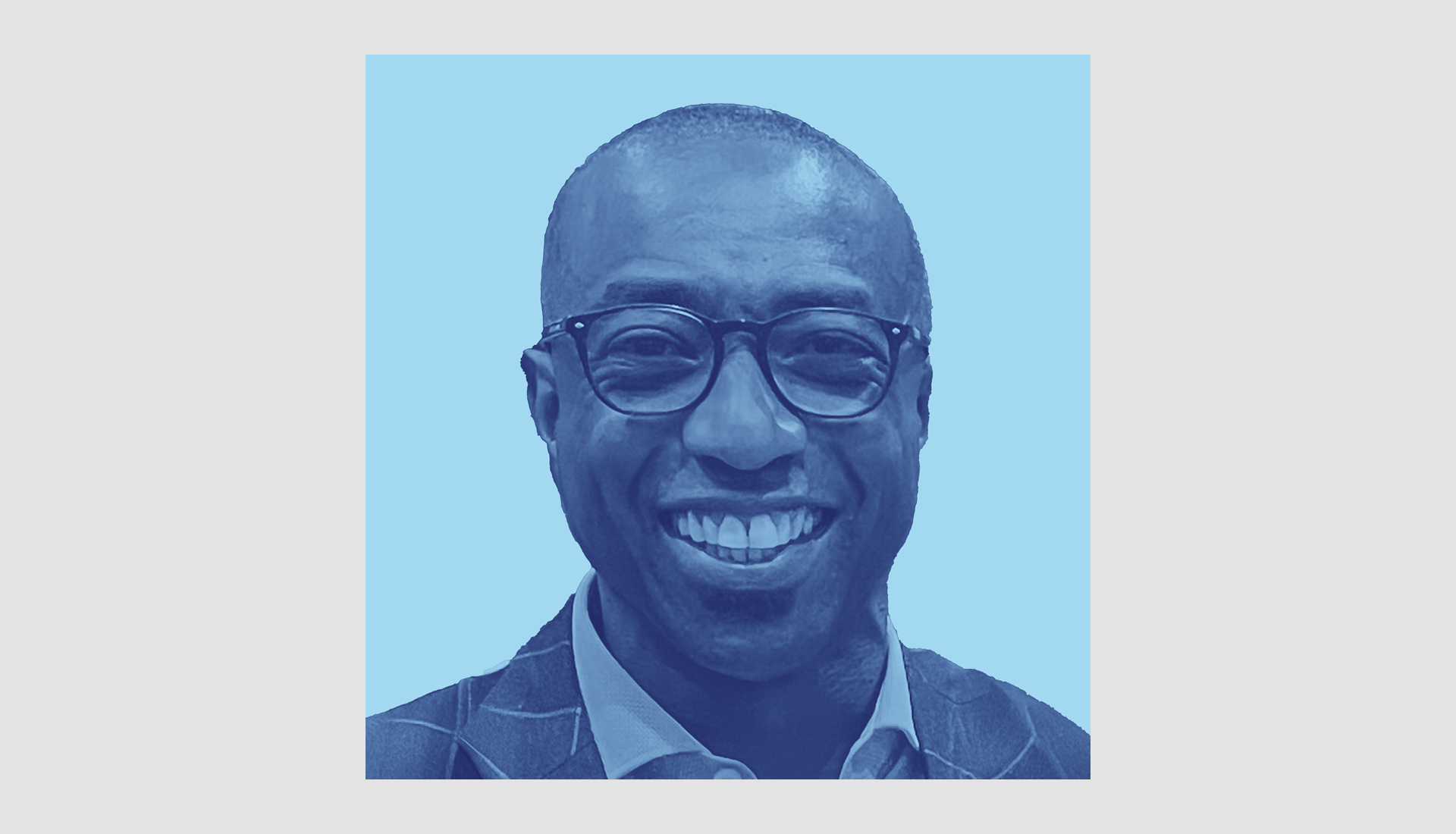 A smiling man wearing glasses and a suit jacket is pictured against a light blue background. The image is colorized in shades of blue.