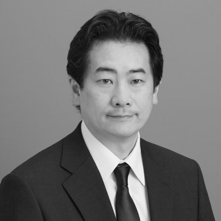 A man with dark hair wearing a suit, white shirt, and dark tie poses for a formal black-and-white portrait against a plain background, reminiscent of the dignified style seen in Edward Boyle Lecture photos.