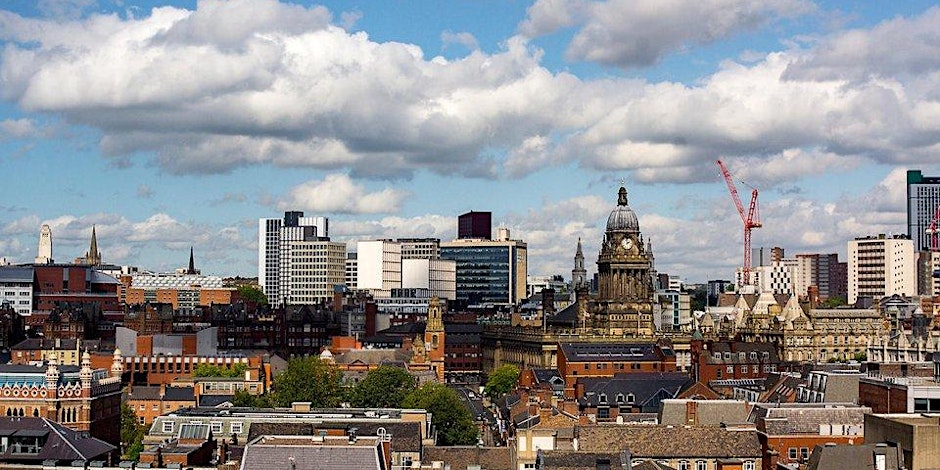 Cityscape of Leeds, UK, featuring a mix of historic and modern buildings, with Leeds Town Hall and a red construction crane visible under a partly cloudy sky.